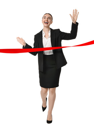 Happy businesswoman crossing red finish line ribbon on white backgroundの写真素材