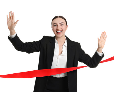 Happy businesswoman crossing red finish line ribbon on white backgroundの写真素材