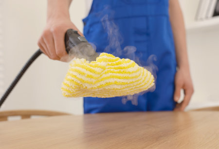 Janitor cleaning wooden surface with steam cleaner at home, closeupの写真素材