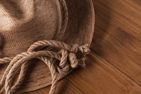 Cotton rope and straw hat on wooden background, closeup. Space for text