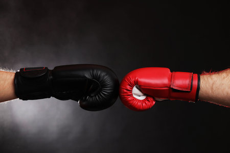 Men in boxing gloves fighting on dark background with smoke, closeupの写真素材