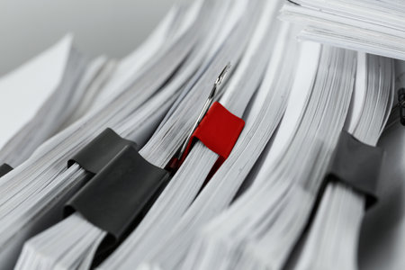 Difference, uniqueness, individuality. Pile of documents with black binder clips and one red, closeupの写真素材