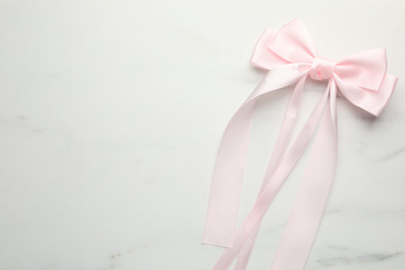Beautiful hair bow on white marble table, top view. Space for text