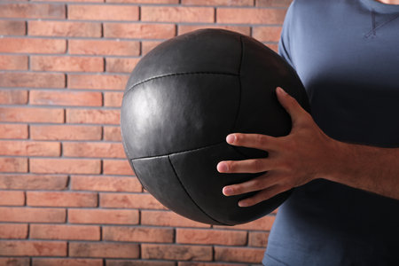 Athletic man with medicine ball near red brick wall, closeupの写真素材