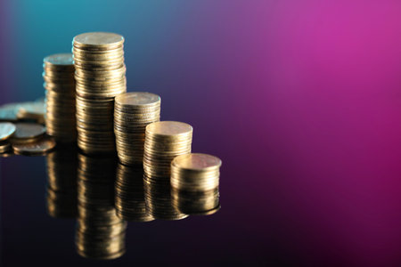 Stacks of coins on color mirror surface, closeup. Space for text