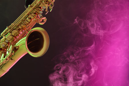 Golden saxophone on color background with smoke, closeup. Space for textの写真素材