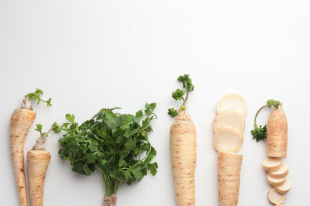 Parsley roots and leaves on white background, flat lay. Space for textの写真素材
