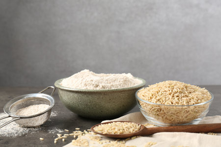 Brown rice, flour and sieve on grey table. Space for textの写真素材