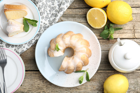 Delicious lemon cake with glaze, mint and citrus fruits on wooden table, flat layの写真素材