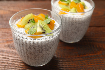 Delicious chia pudding with kiwi, peach and mint in glasses on wooden table, closeupの写真素材
