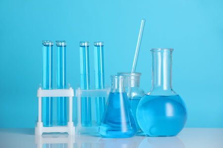 Laboratory glassware with liquid on mirror surface against blue background
