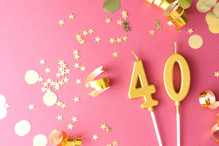 40th birthday. Number shaped candles and confetti on pink background, flat layの写真素材