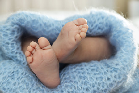 Little baby wrapped in light blue blanket, closeup