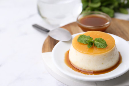 Tasty pudding with caramel sauce served on white marble table, closeup. Space for textの写真素材