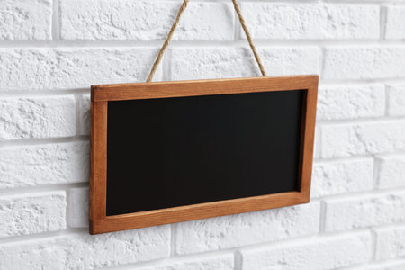 One blank small blackboard on white brick wall