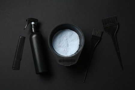 Bleaching powder and hairdresser's tools on black background, flat layの写真素材