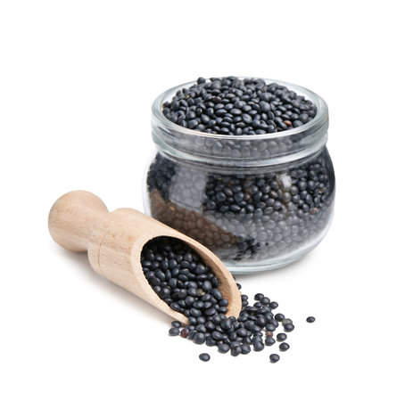 Raw lentils in glass jar and wooden scoop isolated on whiteの写真素材
