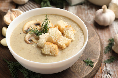 Delicious mushroom cream soup with croutons, dill and ingredients on wooden table, closeupの写真素材