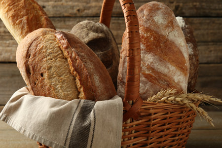 Different loaves of fresh bread in wicker basket on table, closeupの写真素材