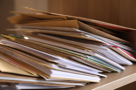 Different paper envelopes on wooden shelf in post office, closeup