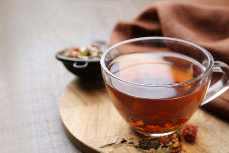 Delicious herbal tea and dry leaves on wooden table, closeup. Space for textの写真素材