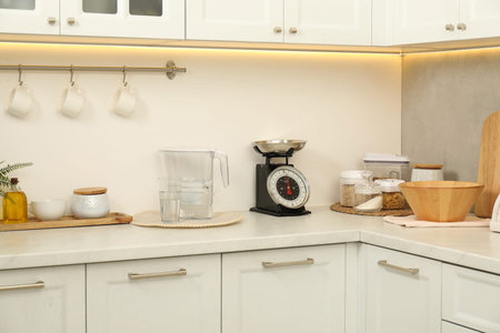 Retro mechanical kitchen scale, different utensils and food products on white marble countertop...