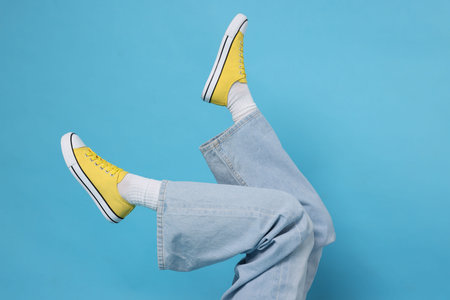 Woman wearing stylish sneakers on light blue background, closeupの写真素材
