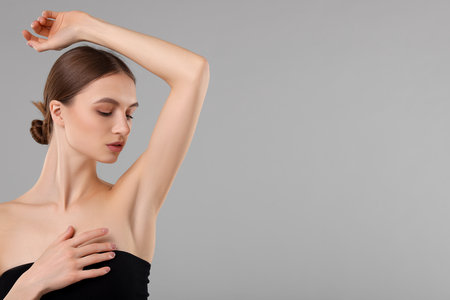 Young woman showing smooth skin after epilation on gray background, space for textの写真素材