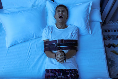 Man in sleepwalking condition screaming on bed, above view