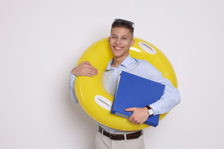 Businessman with inflatable ring and folder on white backgroundの写真素材