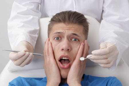 Scared man having appointment with dentist on grey backgroundの写真素材