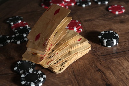 Old vintage playing cards and poker chips on wooden table, closeup