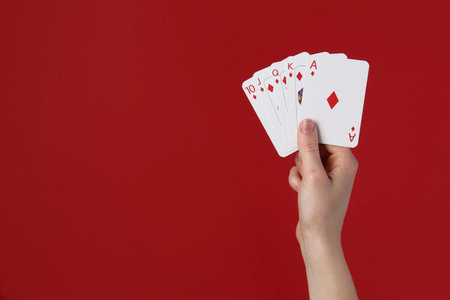 Woman with playing cards against red background, closeup. Space for text