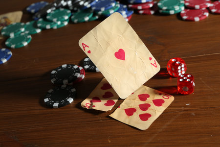 Old vintage playing card, poker chips and dices on wooden table, closeup