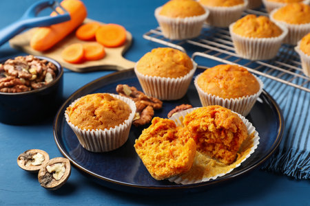 Tasty carrot muffins and walnuts on blue wooden table, closeupの写真素材