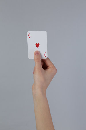 Woman with playing card against grey background, closeupの写真素材