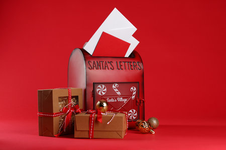 Santa Claus mailbox with letters, gifts and baubles on red background. Christmas traditionの写真素材