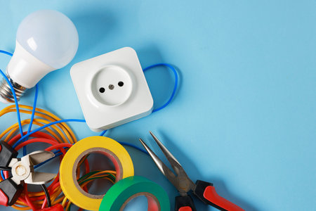 Different electrical tools on light blue background, flat lay. Space for text