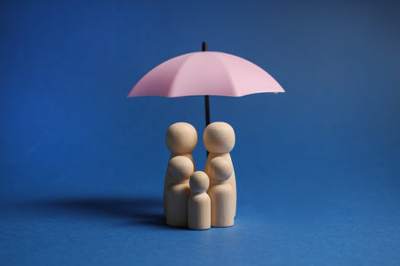 Human figures under umbrella on blue background. Insurance conceptの写真素材