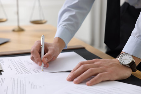 Notary signing document at table in office, closeup