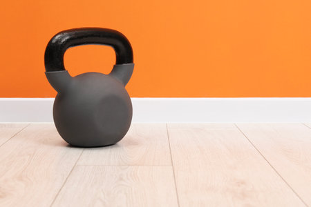 One kettlebell on floor near orange wall. Space for textの写真素材
