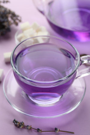 Aromatic lavender tea in glass cup and dry flowers on lilac background, closeupの写真素材