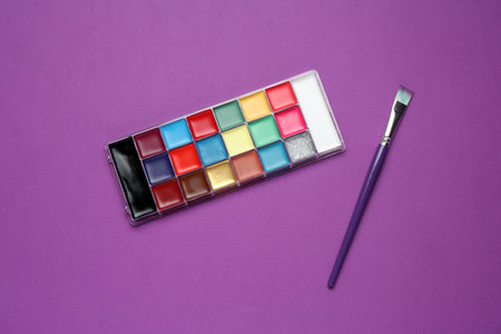 Face paints and brush on purple background, top viewの写真素材