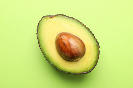 One cut ripe avocado on light green background, top viewの写真素材
