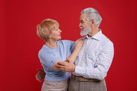 Lovely senior couple looking at each other on red background