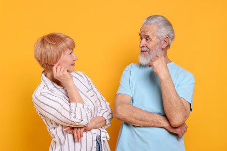 Senior couple looking at each other on orange backgroundの写真素材
