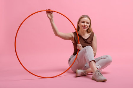 Beautiful young woman with hula hoop on pink backgroundの写真素材