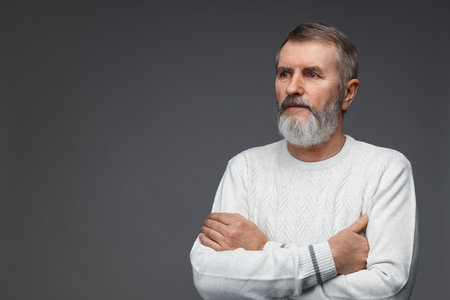 Portrait of mature man with crossed arms on grey background, space for textの写真素材