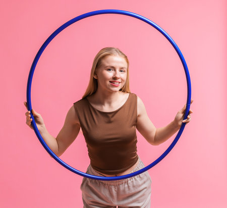 Beautiful young woman with hula hoop on pink background, space for textの写真素材