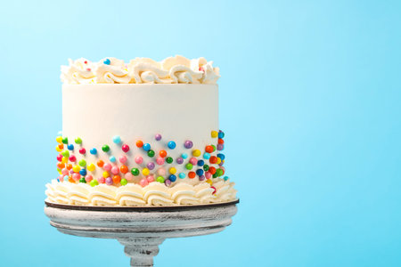 Delicious cake with colorful sprinkles on light blue background, space for text